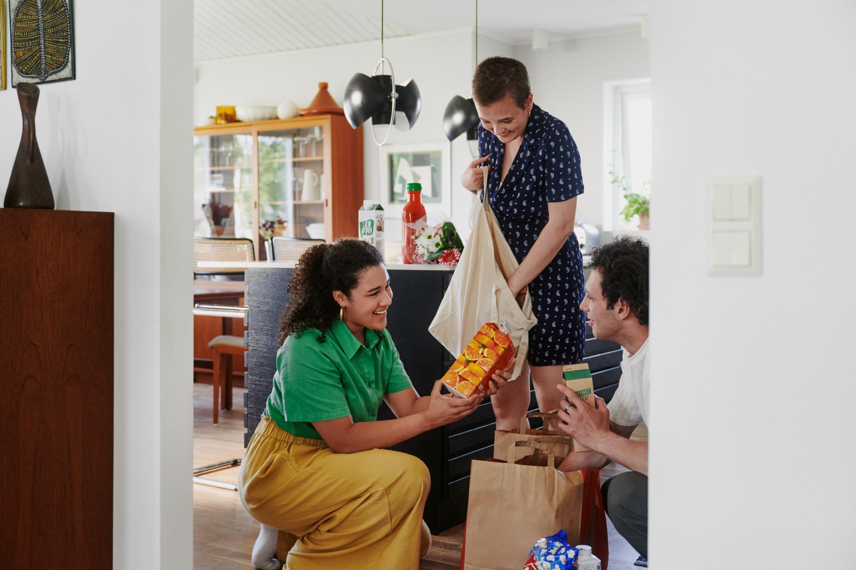 Unga vuxna packar upp matvaror i ett kök